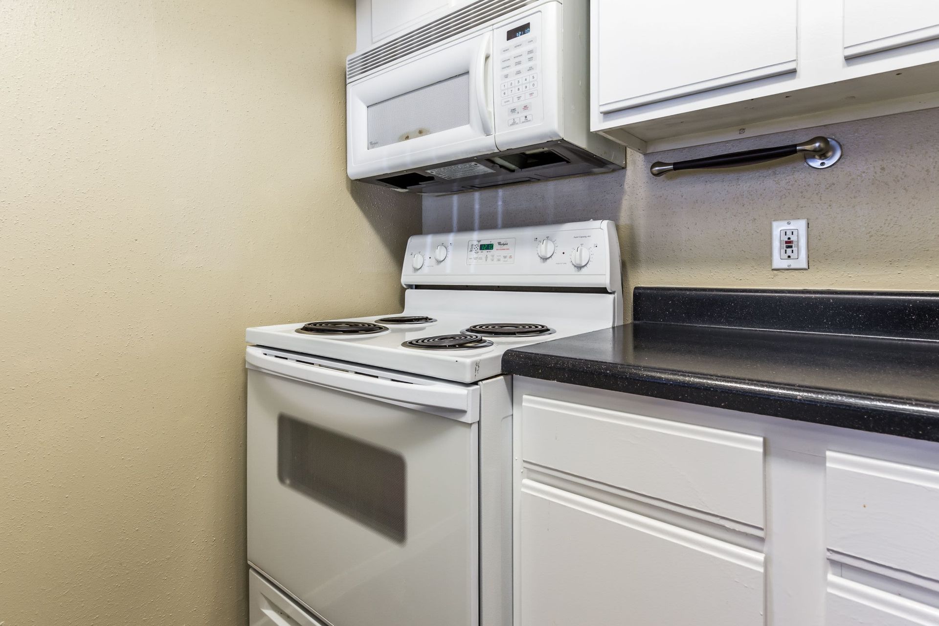 Apartment kitchen with a stove, microwave, plenty of counter space, and cabinets at SoCo on the Lake in Austin, TX.