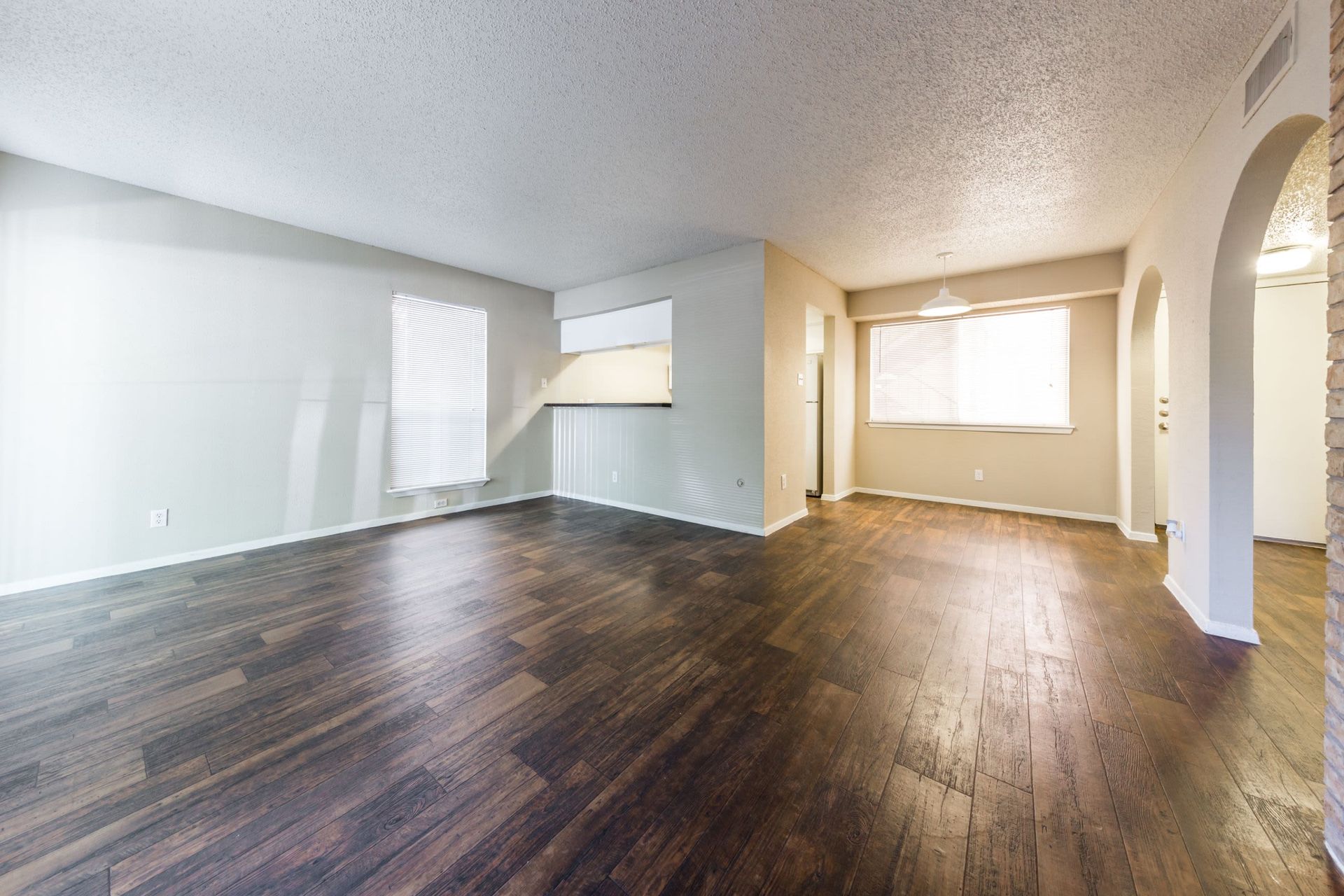 An empty living room with hardwood floors and white walls at SoCo on the Lake in Austin, TX.