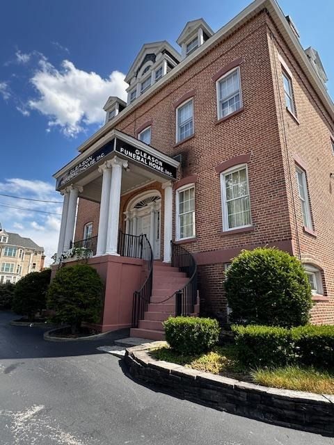 Brick building with white columns and front steps under a blue sky