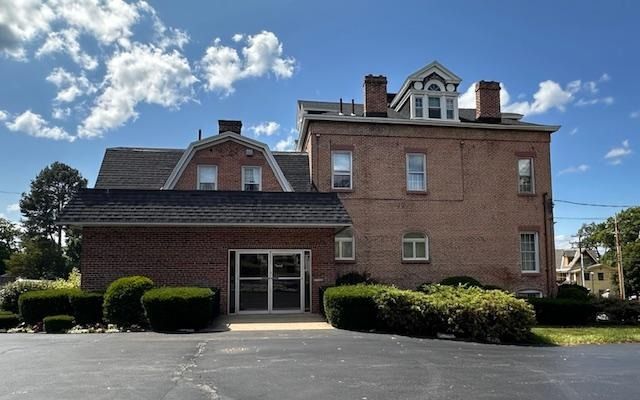 Brick building with a low entrance and small bushes under a partly cloudy blue sky
