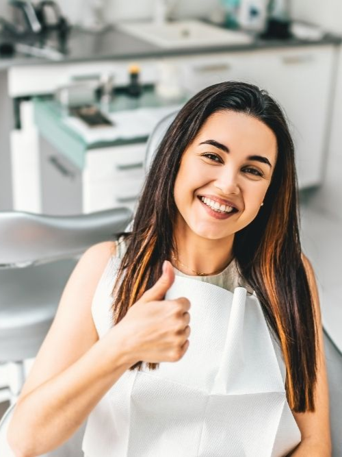 Dentist showing a model of teeth to a patient in a dental office. Both smiling.