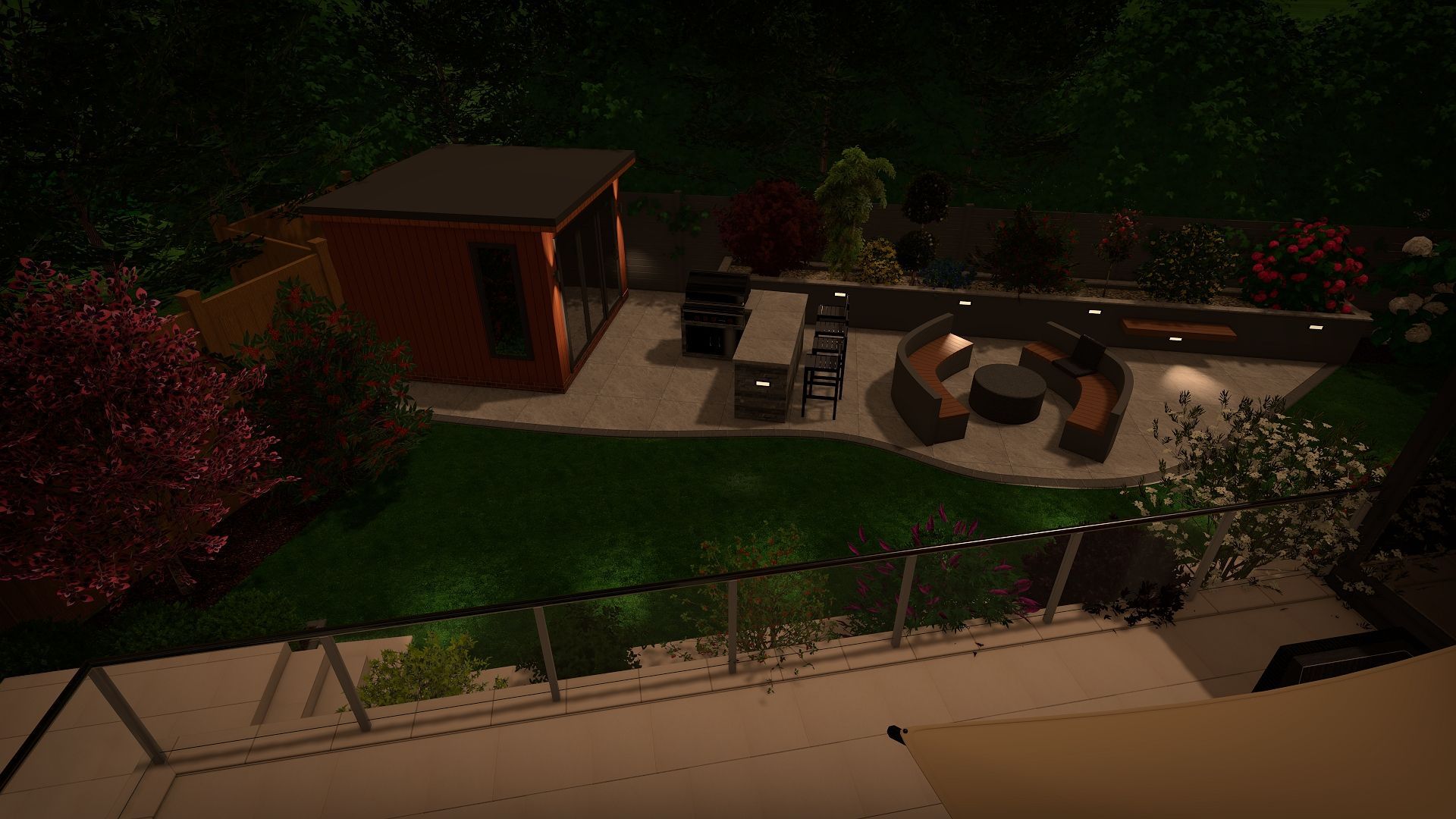 Nighttime view of a backyard patio with seating areas, landscaping, and a small orange building.