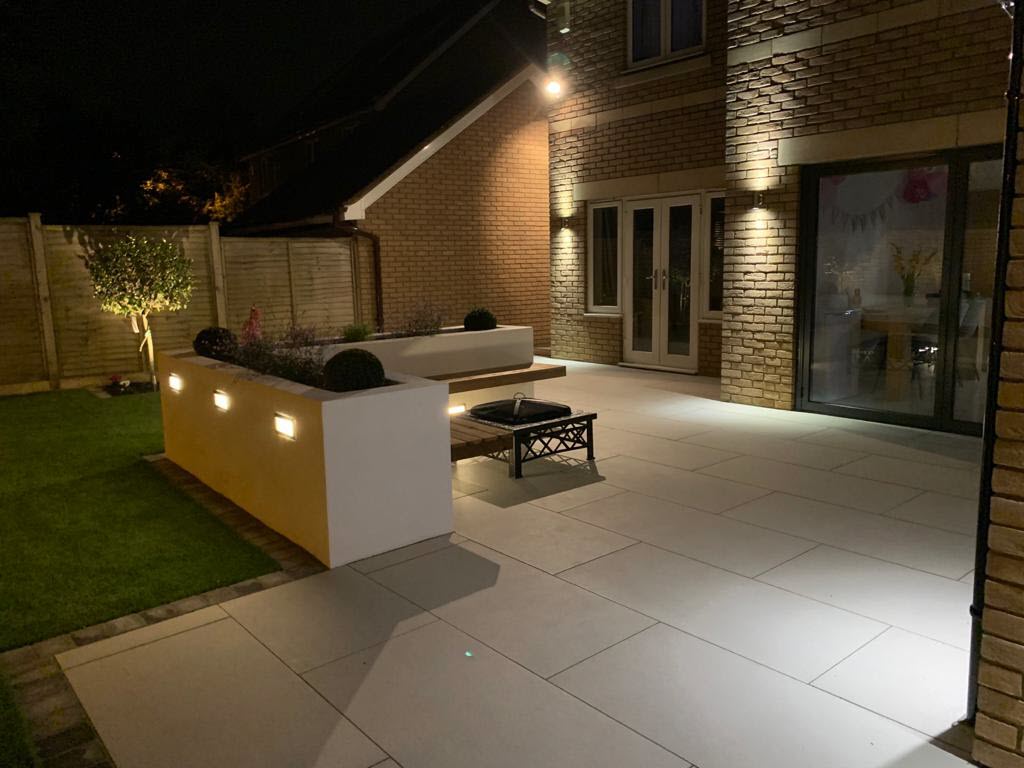 A patio with a table and chairs is lit up at night.