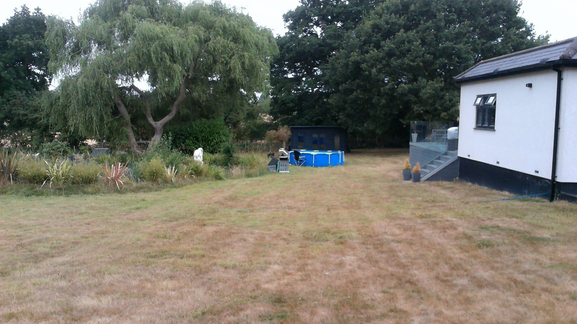 A white house is sitting in the middle of a lush green field.