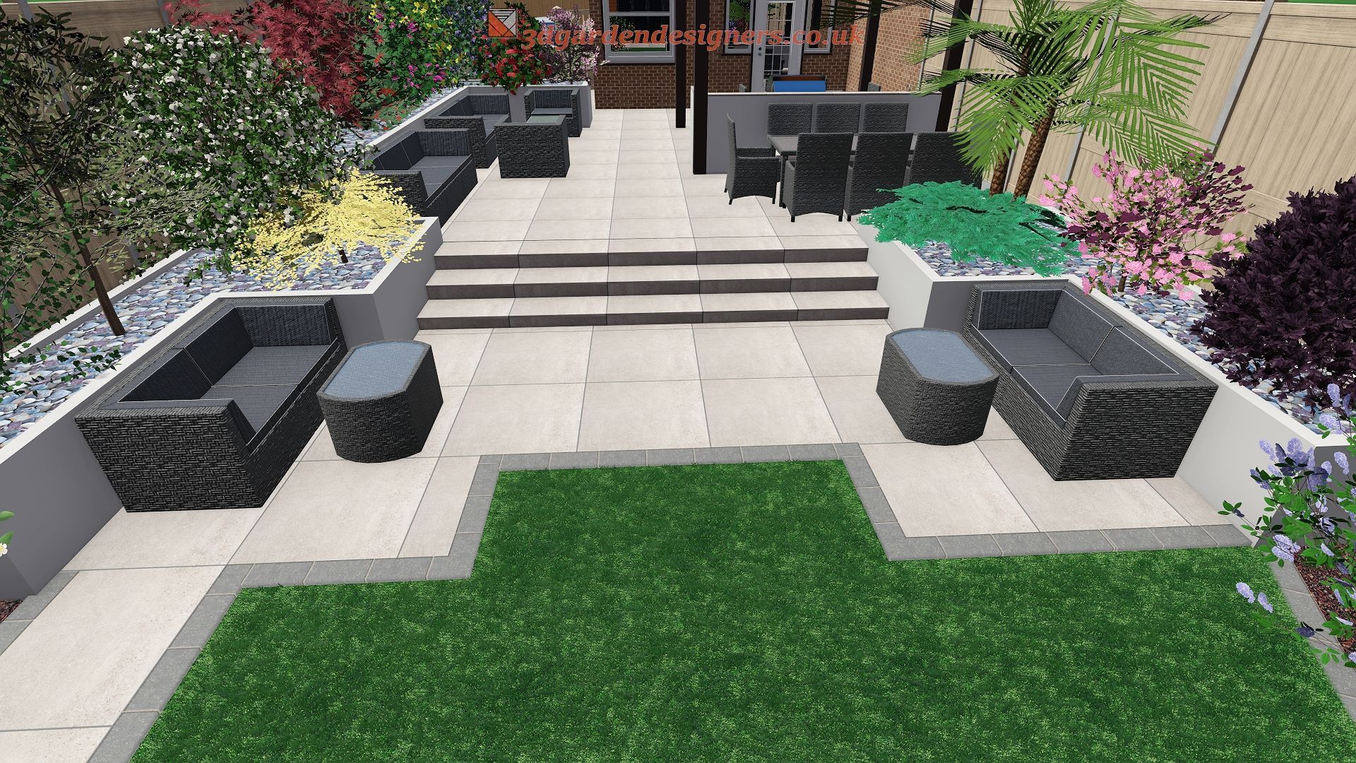 Outdoor patio with seating, steps, and landscaping. Dark gray furniture, light stone patio, green grass, and colorful plants.