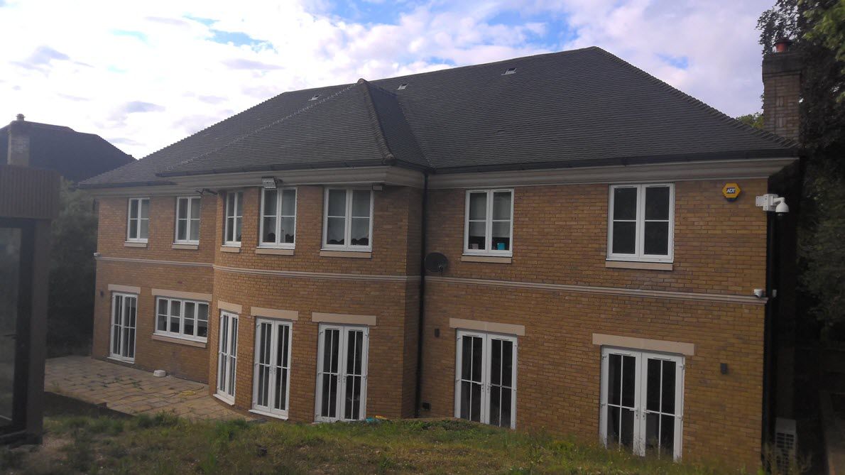 A large brick house with a black roof and white windows