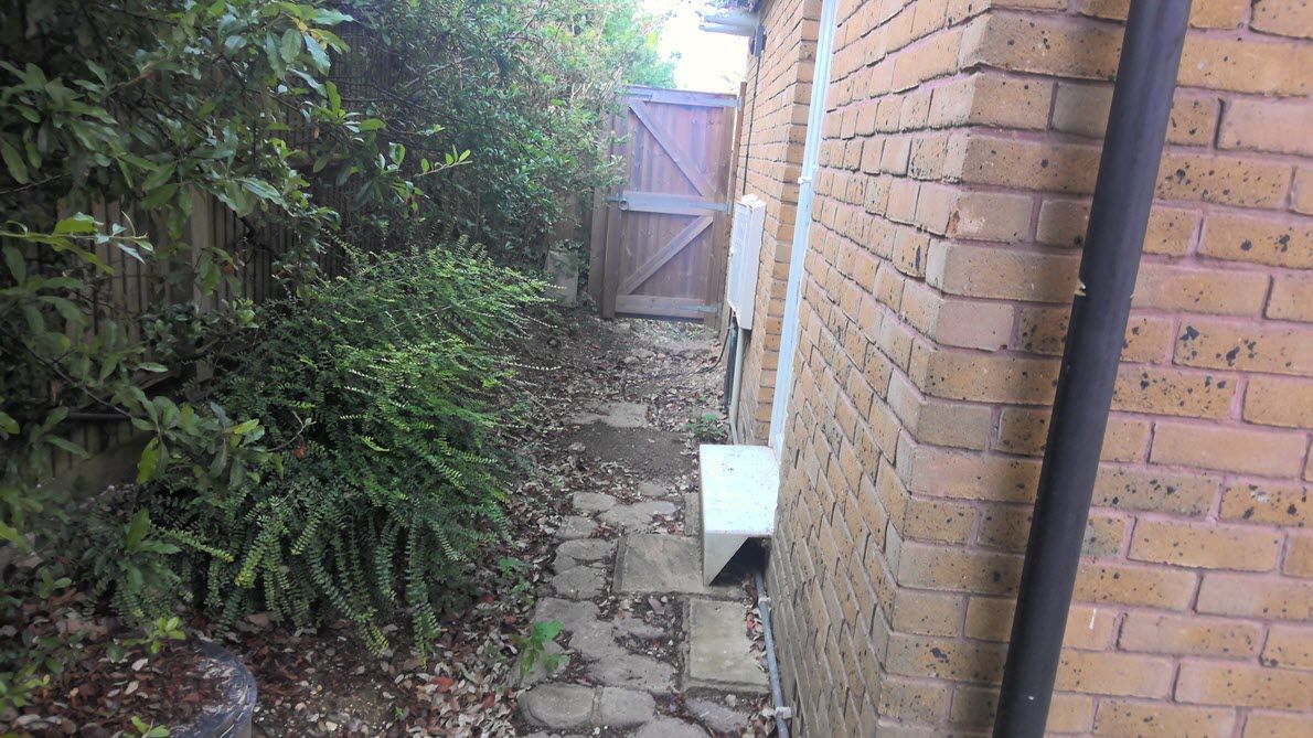 A brick building with a wooden gate in the backyard.