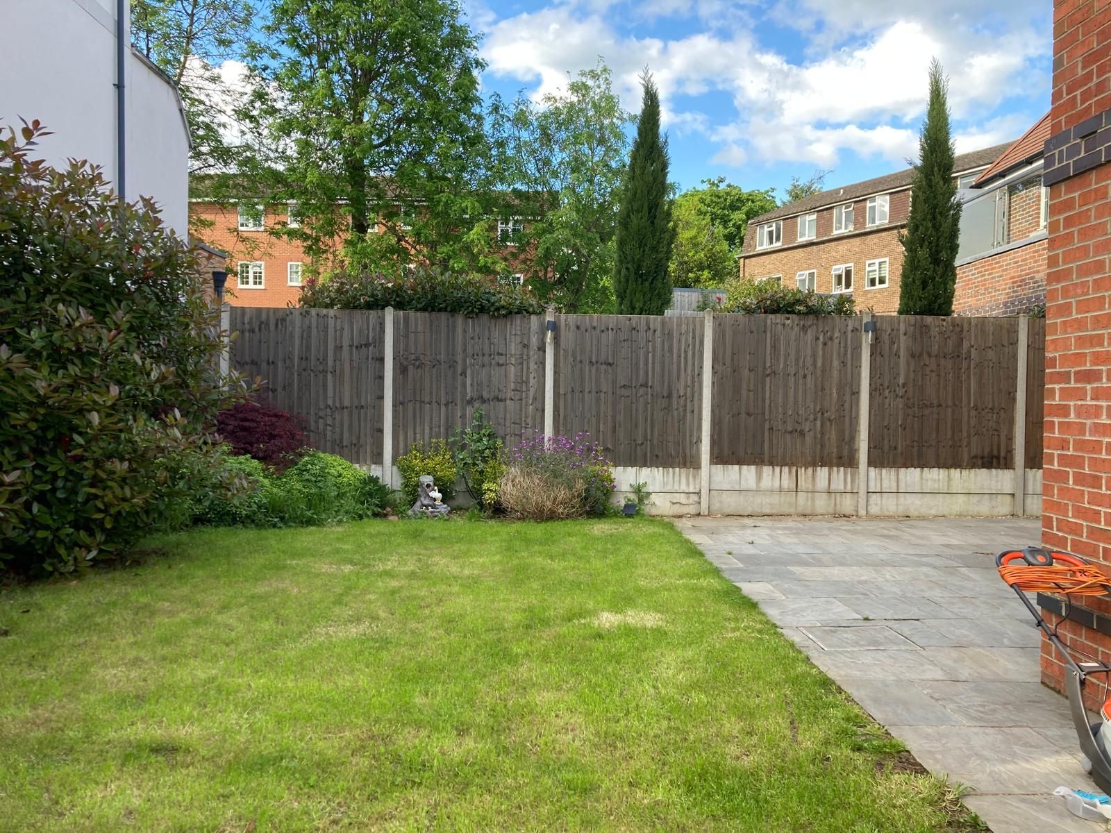 A backyard with a wooden fence and a brick building in the background.