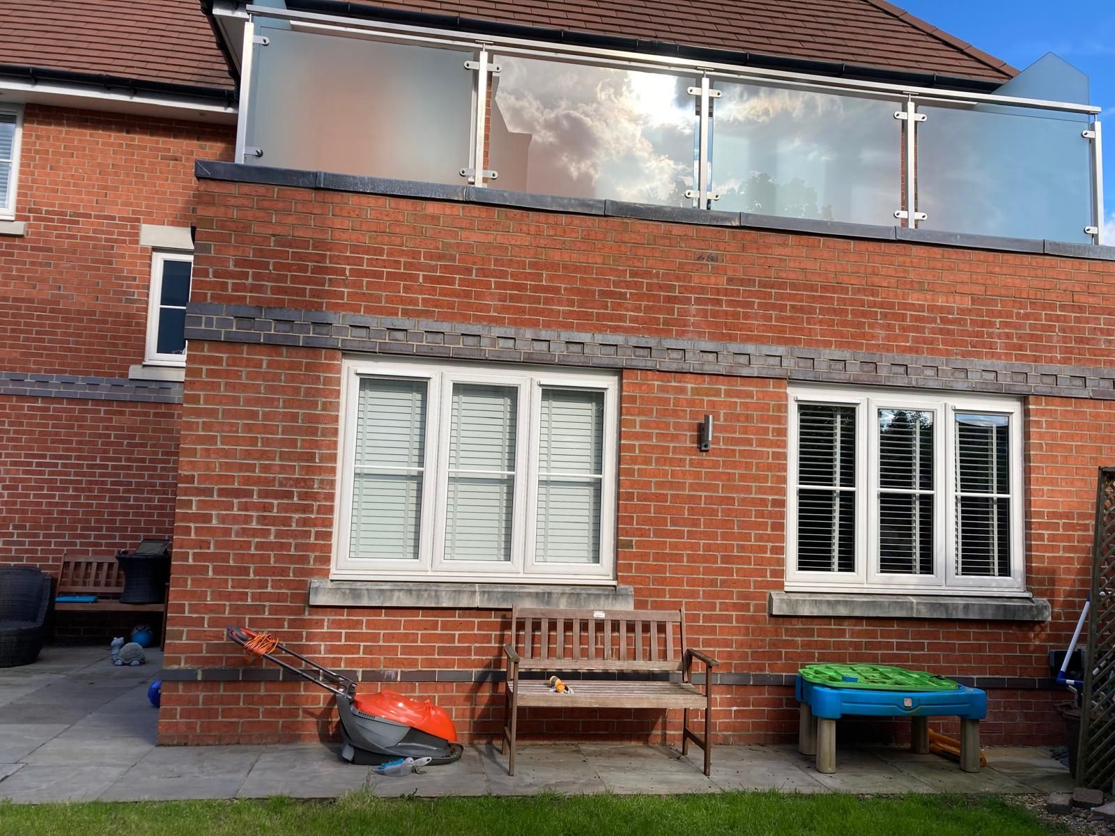 A brick house with a balcony and a bench in front of it.