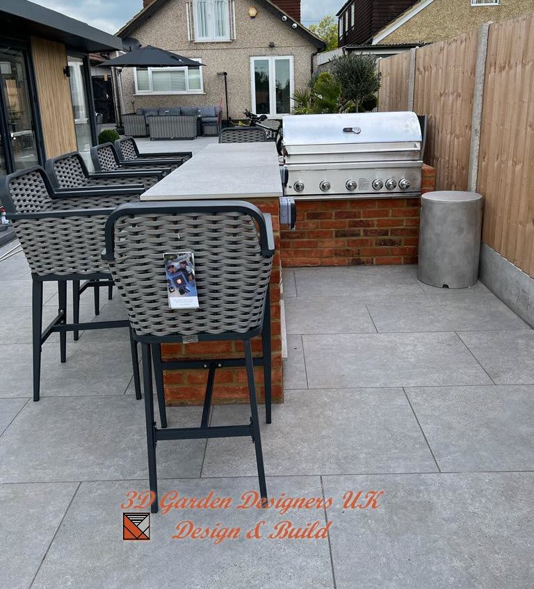 A patio with wicker chairs and a grill from garden designers uk