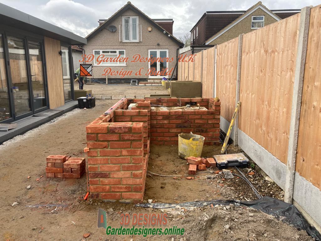 A brick wall is being built in the backyard of a house.