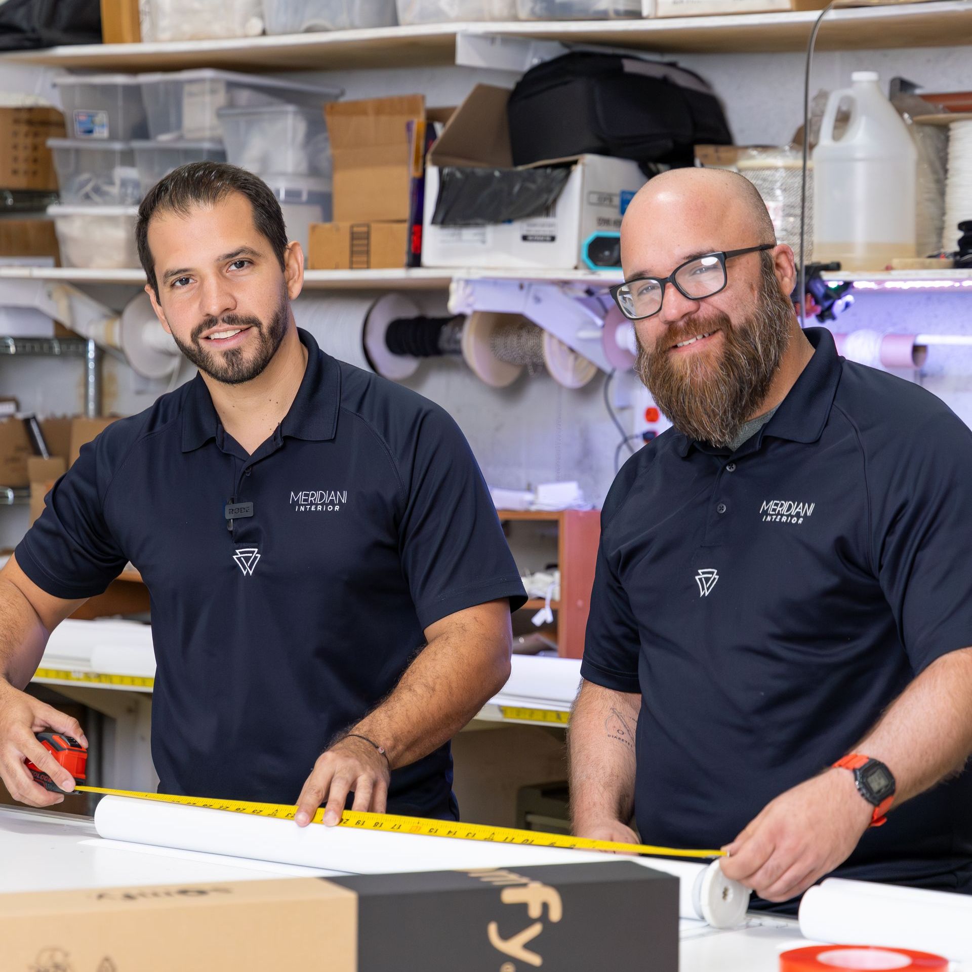 Two men are standing next to each other and one of them is measuring something with a tape measure