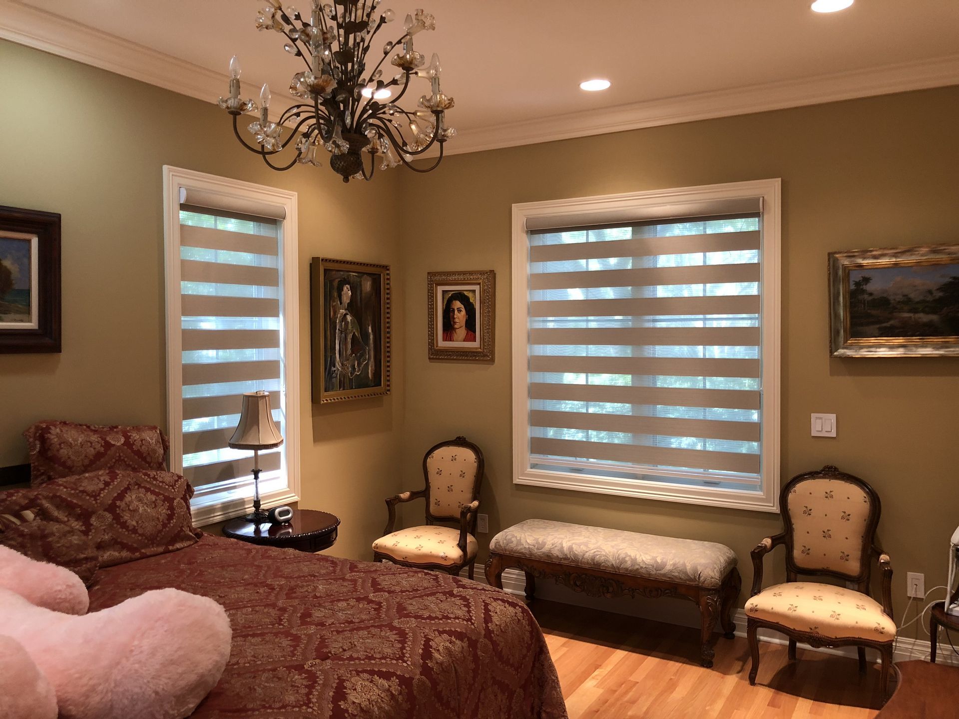 A bedroom with a bed , chairs , a bench and a chandelier.