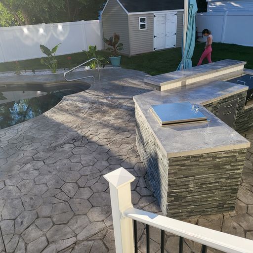 A woman is standing on a patio next to a pool