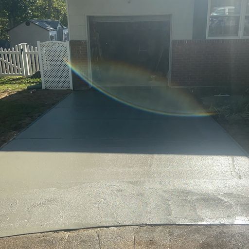 A concrete driveway leading to a garage with a rainbow in the background