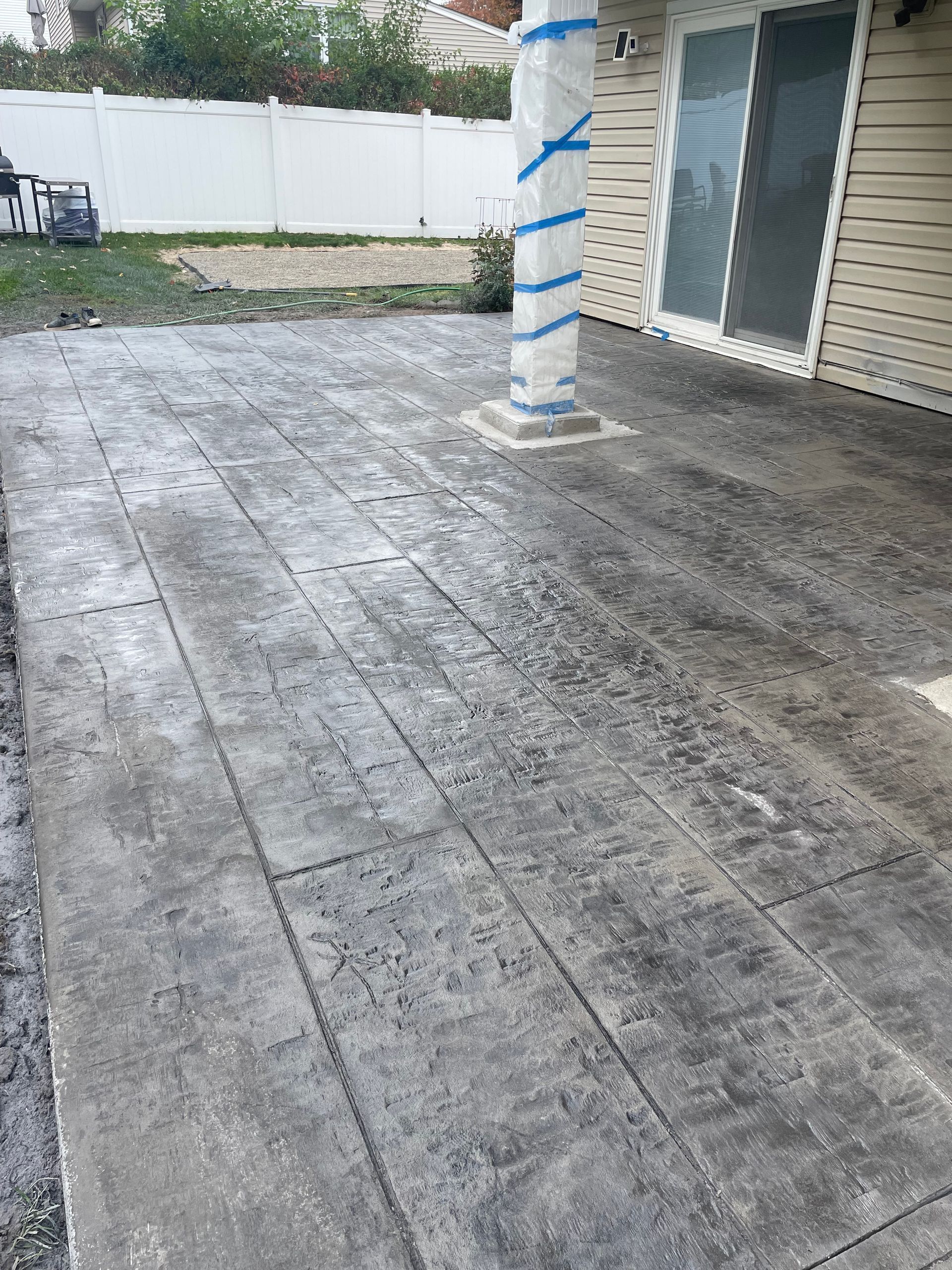 A concrete patio with a pillar in the middle of it in front of a house.