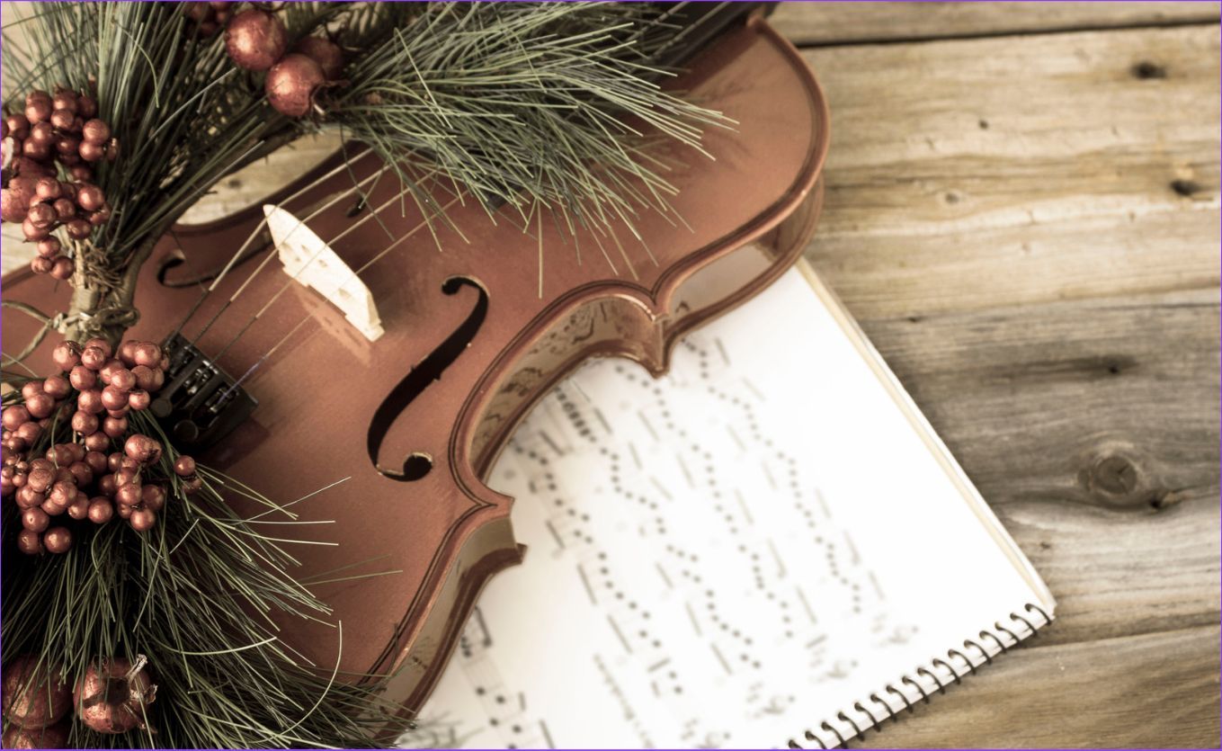 A festive image of a violin and sheet music decorated with Christmas greenery.