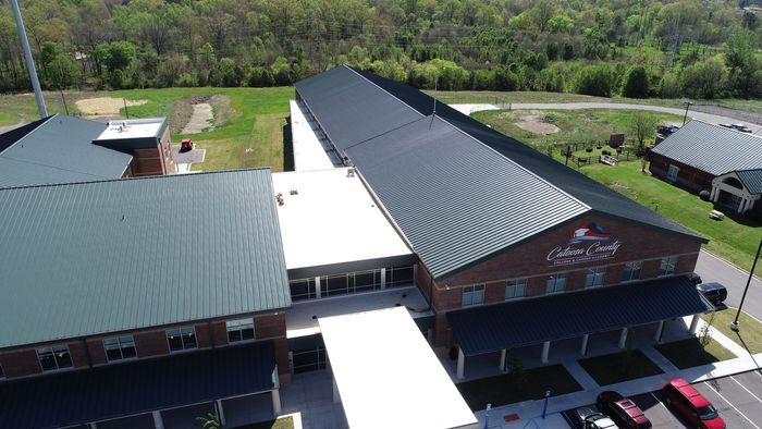 An aerial view of a large brick building with a black roof