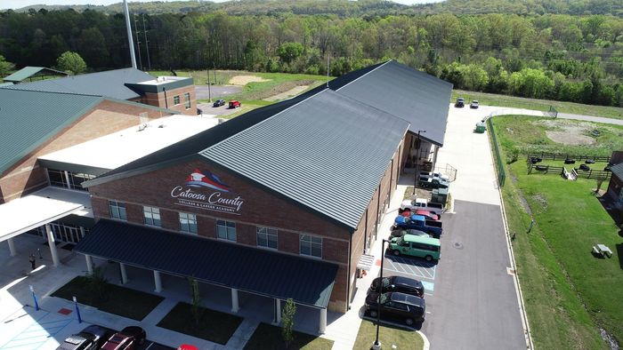 An aerial view of a large brick building with cars parked in front of it.