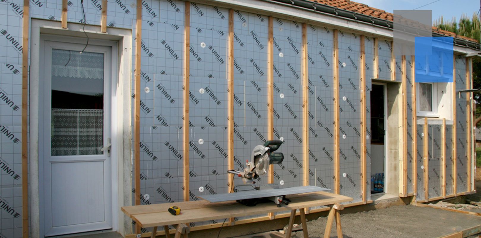 Une maison est en train d'être construite avec une scie circulaire devant elle.