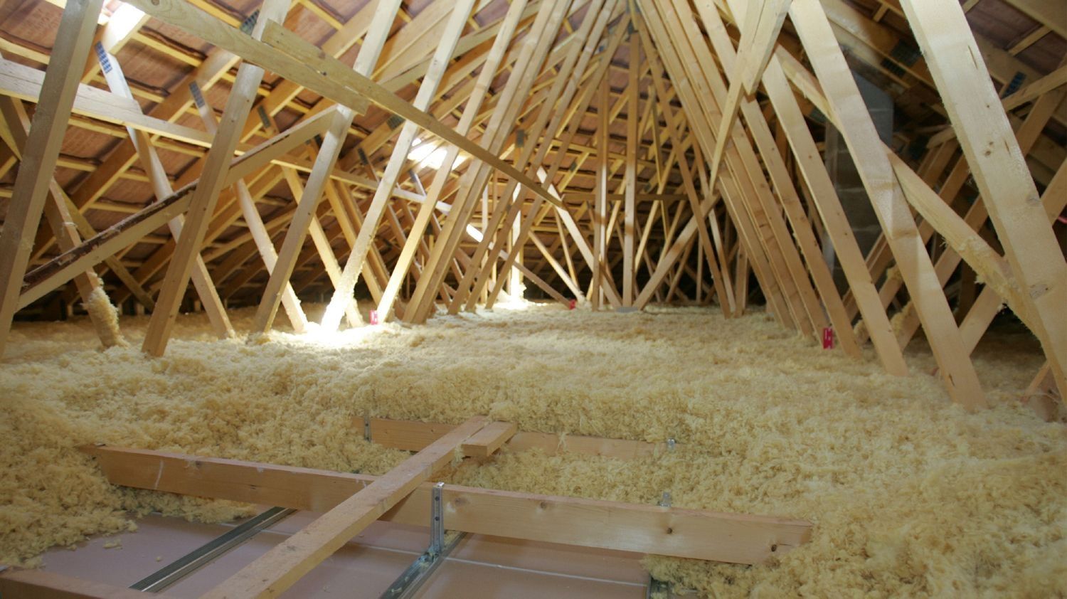 Le grenier d'une maison en construction est rempli de poutres et de copeaux de bois.