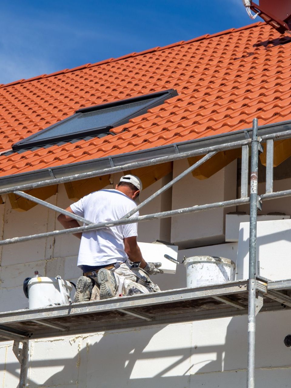 Un homme peint le côté d'un bâtiment sur un échafaudage.