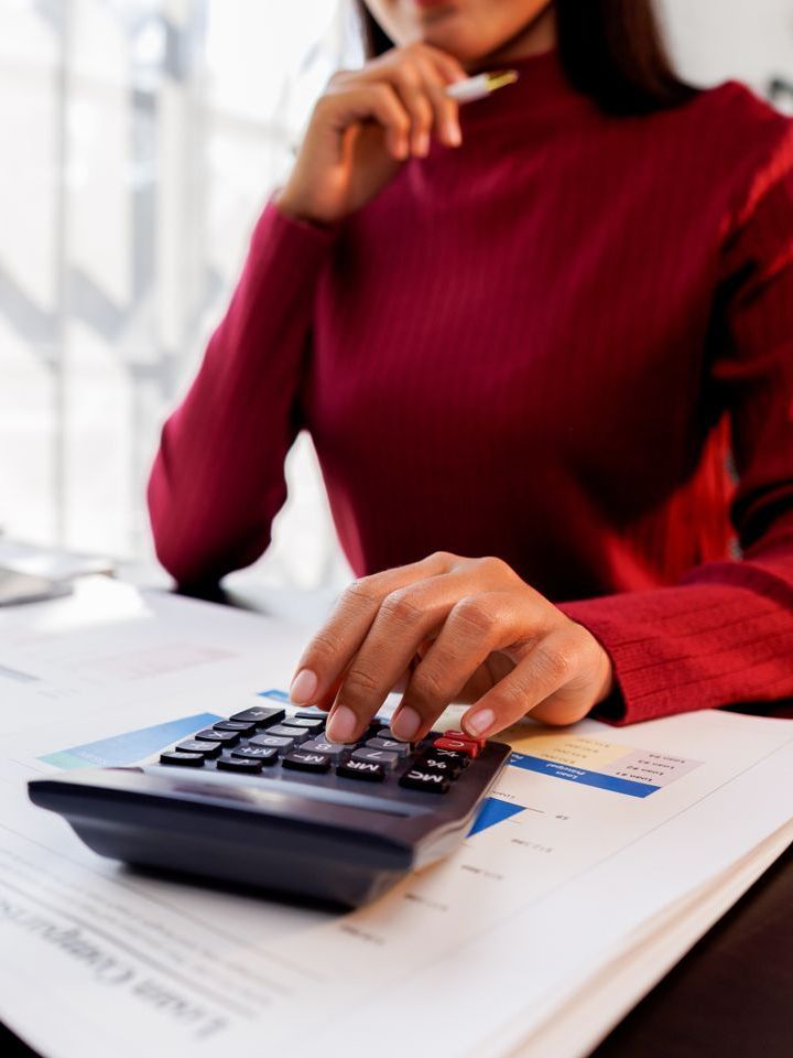 Une femme en pull rouge utilise une calculatrice