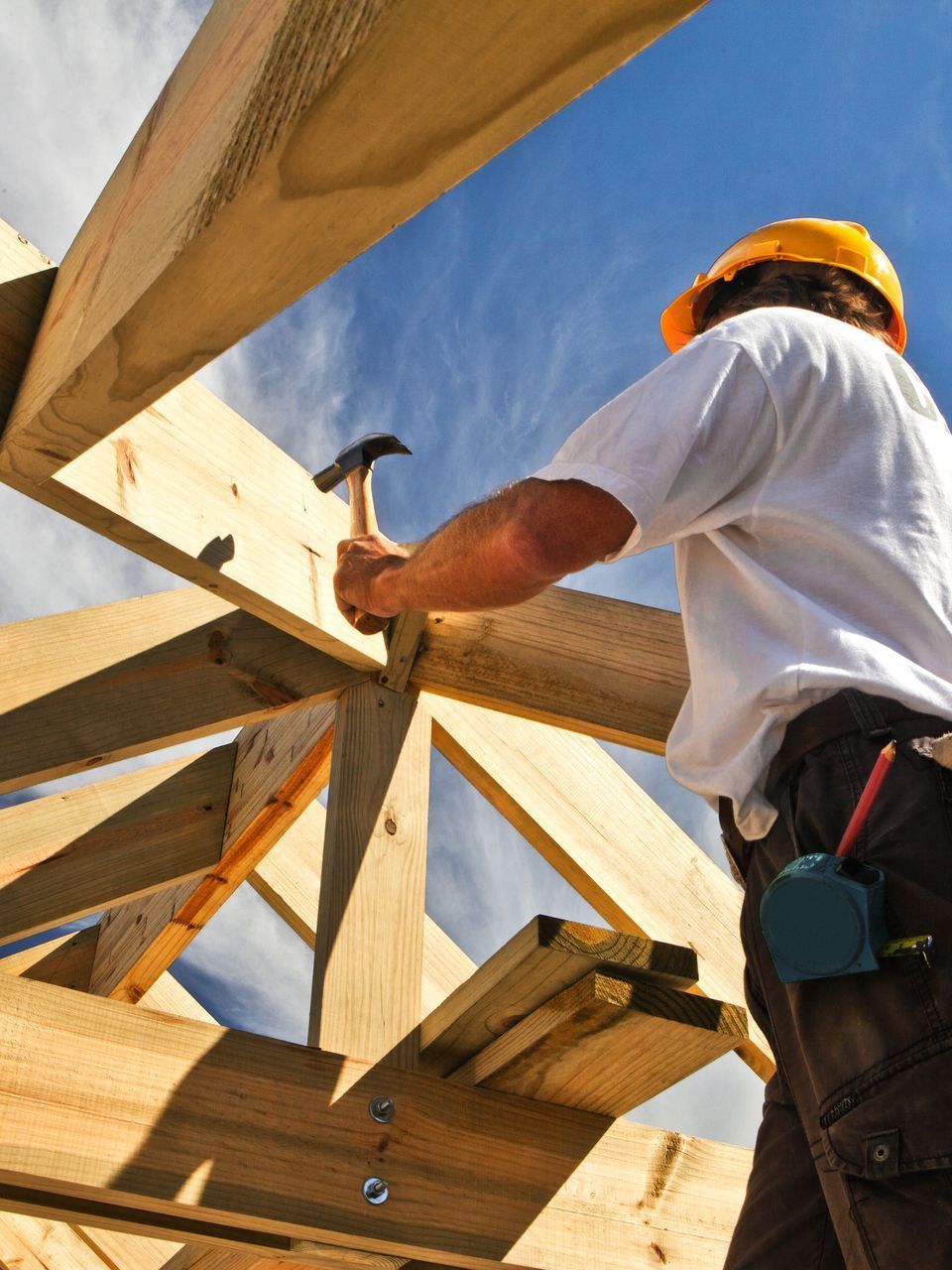 Un homme portant un casque de chantier martèle un morceau de bois