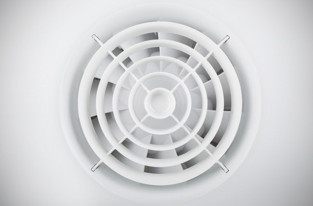 Un gros plan d'un ventilateur blanc sur un mur blanc.