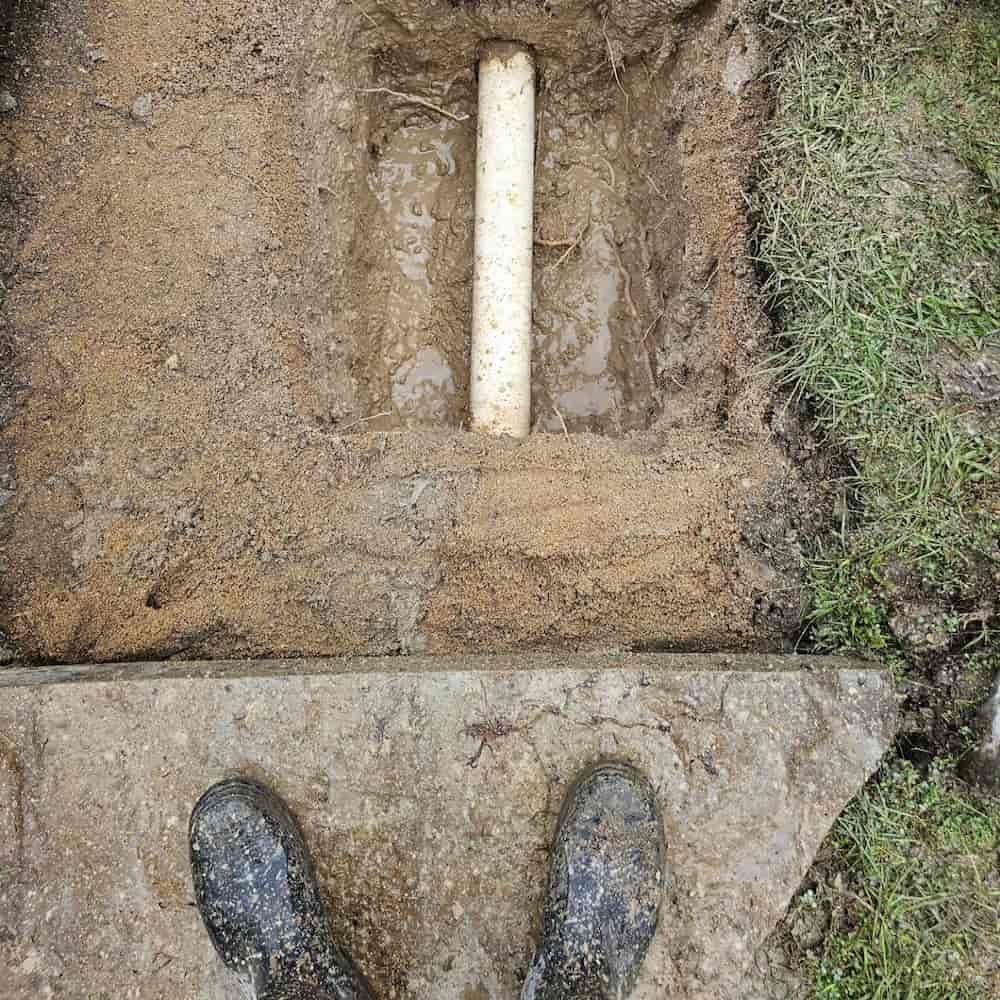 A Person Is Standing In The Dirt Next To A Pipe In The Ground — ViperVac Solutions PTY LTD in Bowen, QLD