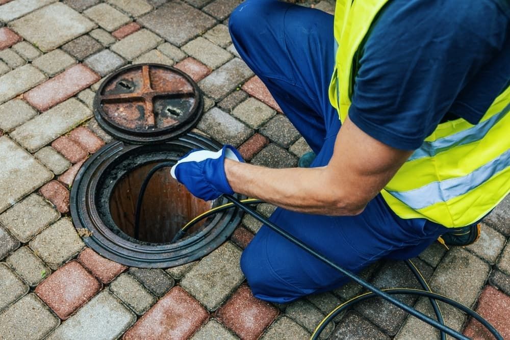 A Man Is Kneeling Down In Front Of A Manhole Cover — ViperVac Solutions PTY LTD in Cannonvale, QLD