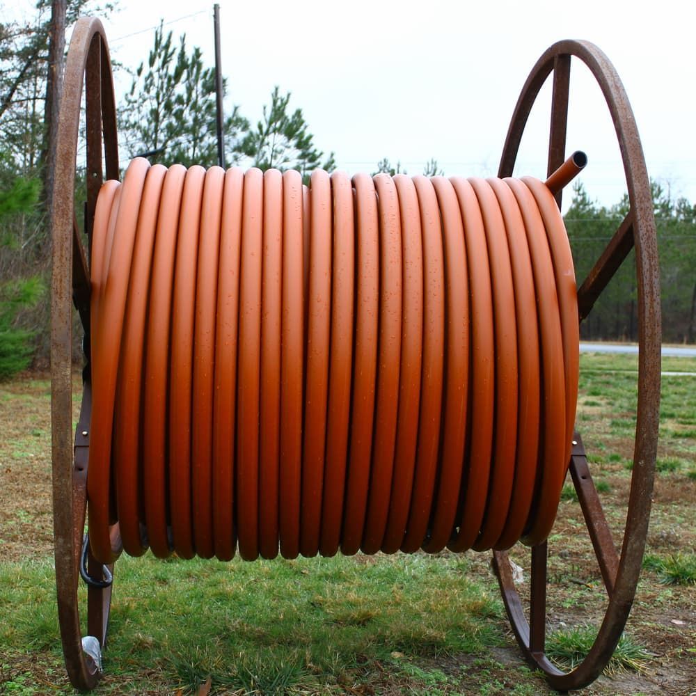 A Large Spool Of Orange Hose Is Sitting In The Grass — ViperVac Solutions PTY LTD in Cannonvale, QLD