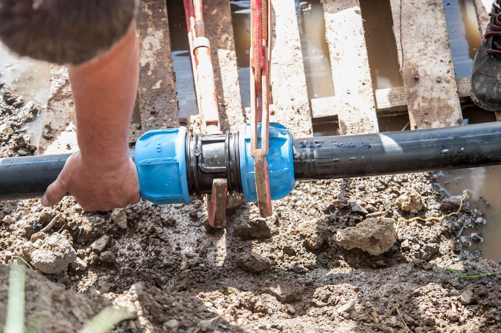 A Man Is Fixing A Water Pipe In The Dirt — ViperVac Solutions PTY LTD in Cannonvale, QLD