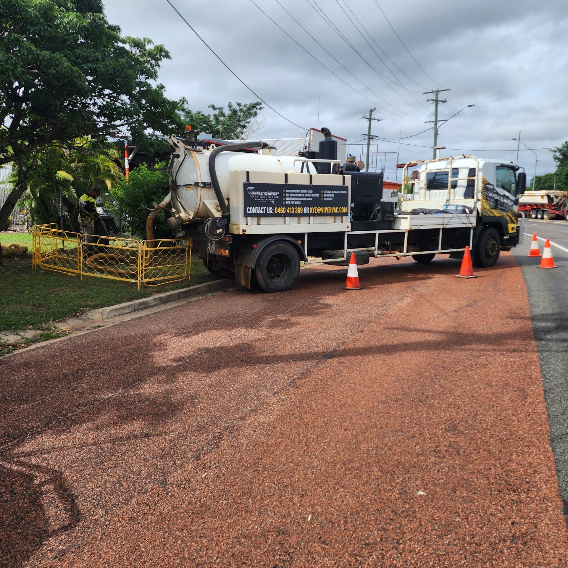 Truck applying red surfacing to a road, cones set up. White tank truck with black wheels — ViperVac Solutions PTY LTD in Cannonvale, QLD