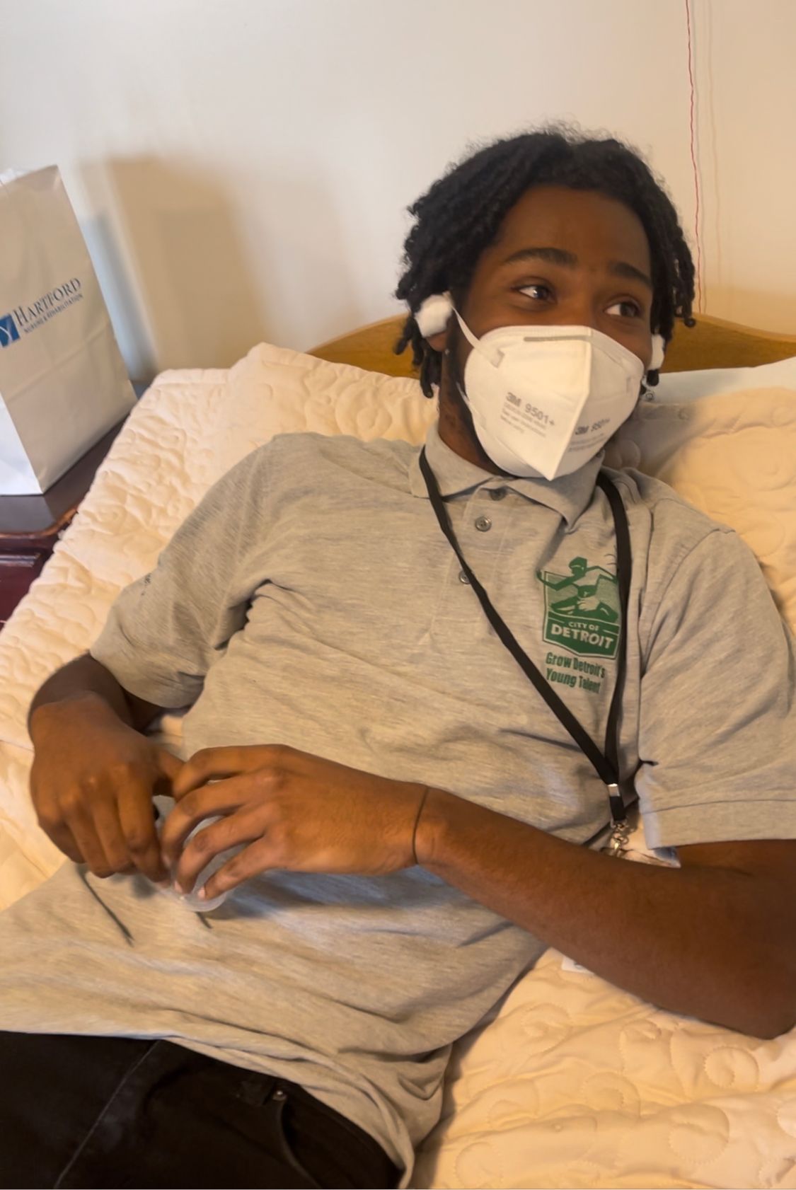 A man wearing a mask is laying on a bed.