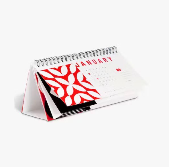 a calendar with a red and white design on it is sitting on a table .