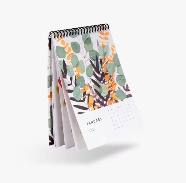 a spiral bound calendar with a floral design on it .