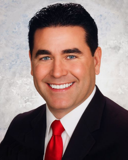 A woman wearing a black shirt and a necklace is smiling for the camera.
