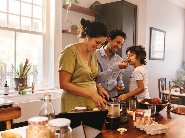 A family is preparing food together in a kitchen.