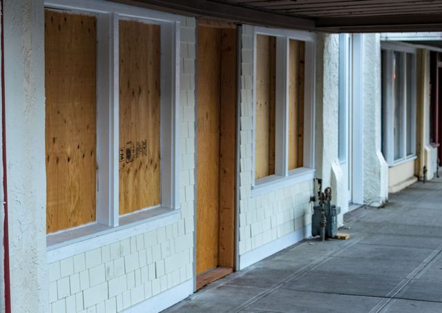 A row of motel rooms with boarded up windows and doors.