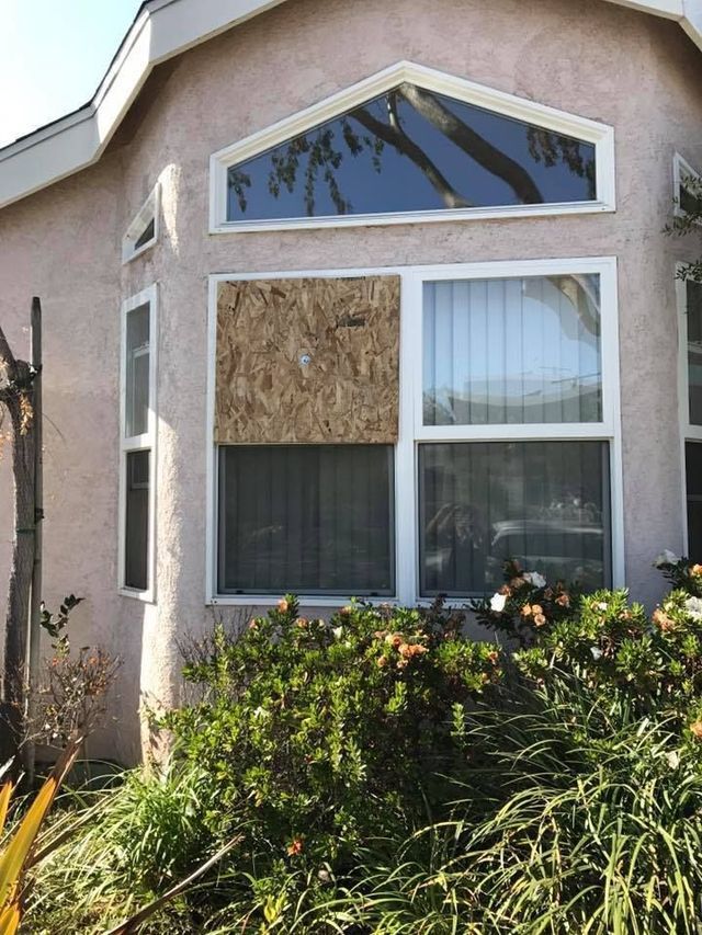 A house with a large window that has been boarded up.