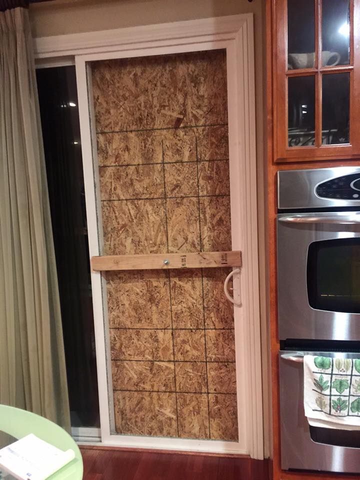 A kitchen with a sliding glass door covered in plywood.