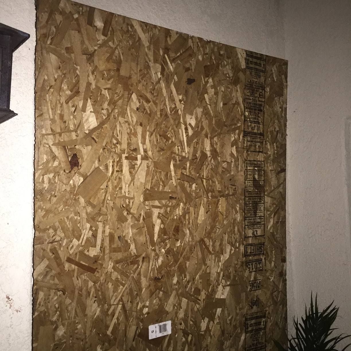 A piece of plywood is sitting on a wall next to a plant