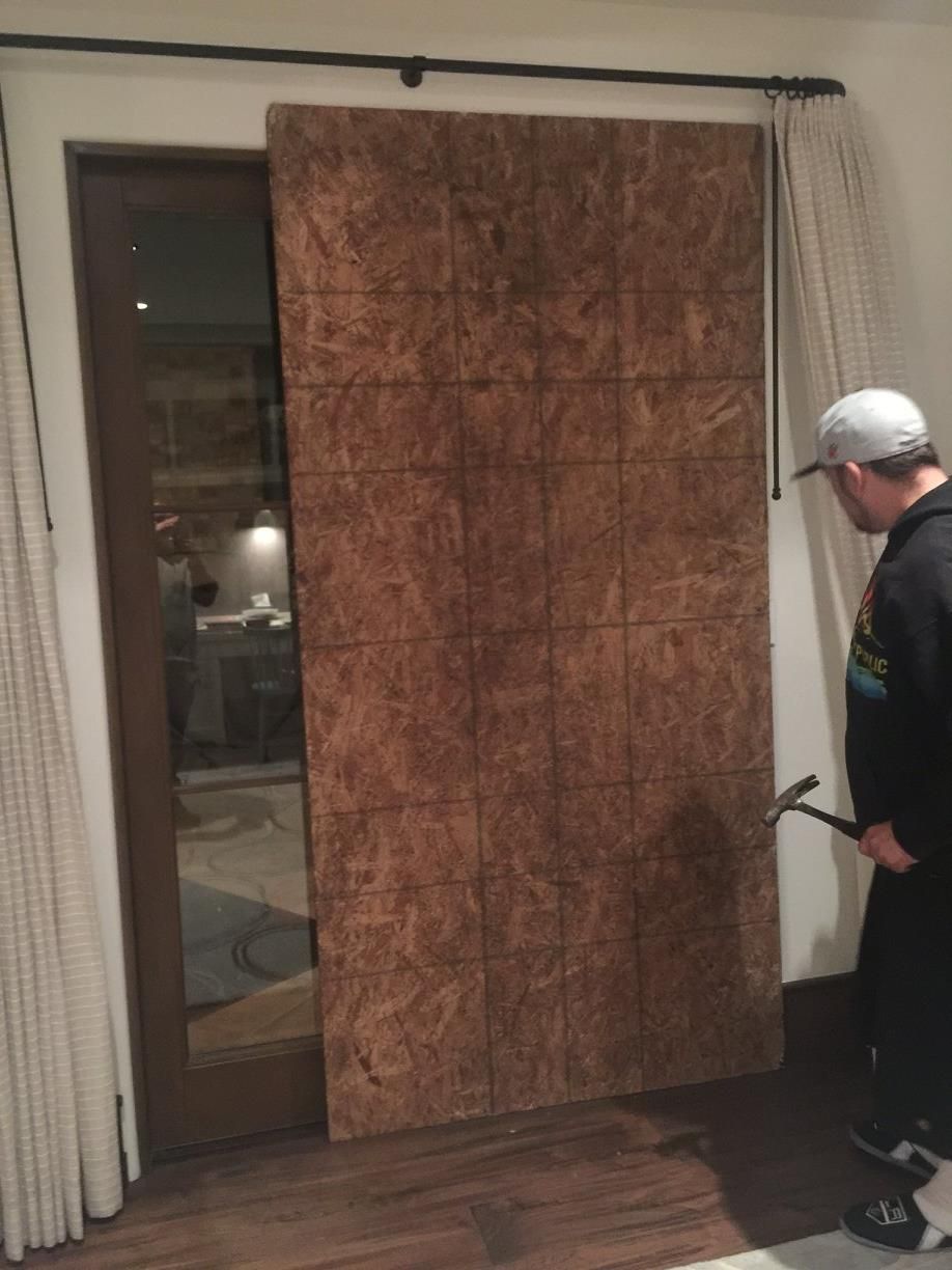 A man is standing in front of a sliding door holding a hammer.