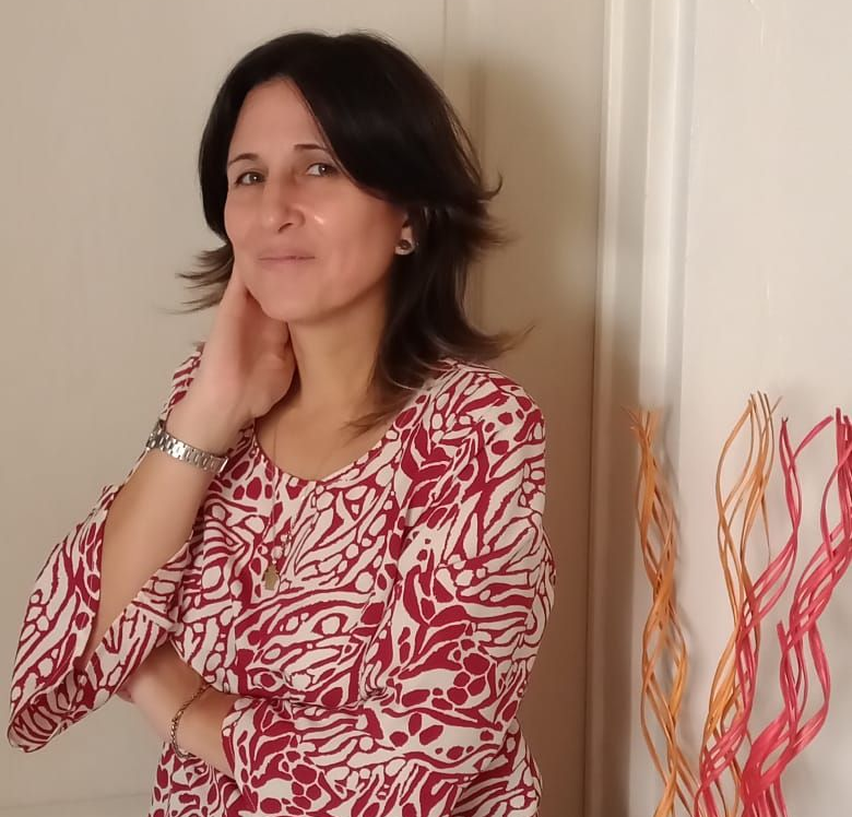 Una mujer con traje gris señala un documento mientras habla con un hombre sentado a una mesa.