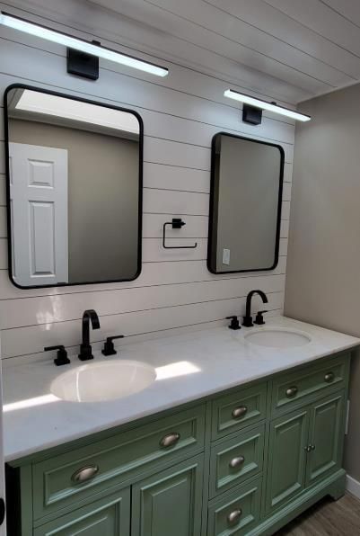 Bathroom with two sinks, sage green vanity, white countertop, black fixtures, and mirrors.