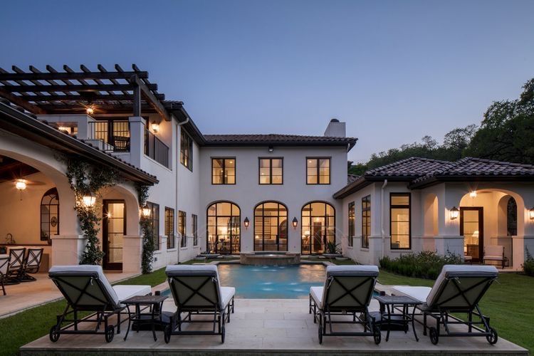 A large white custom  home with a swimming pool in the backyard