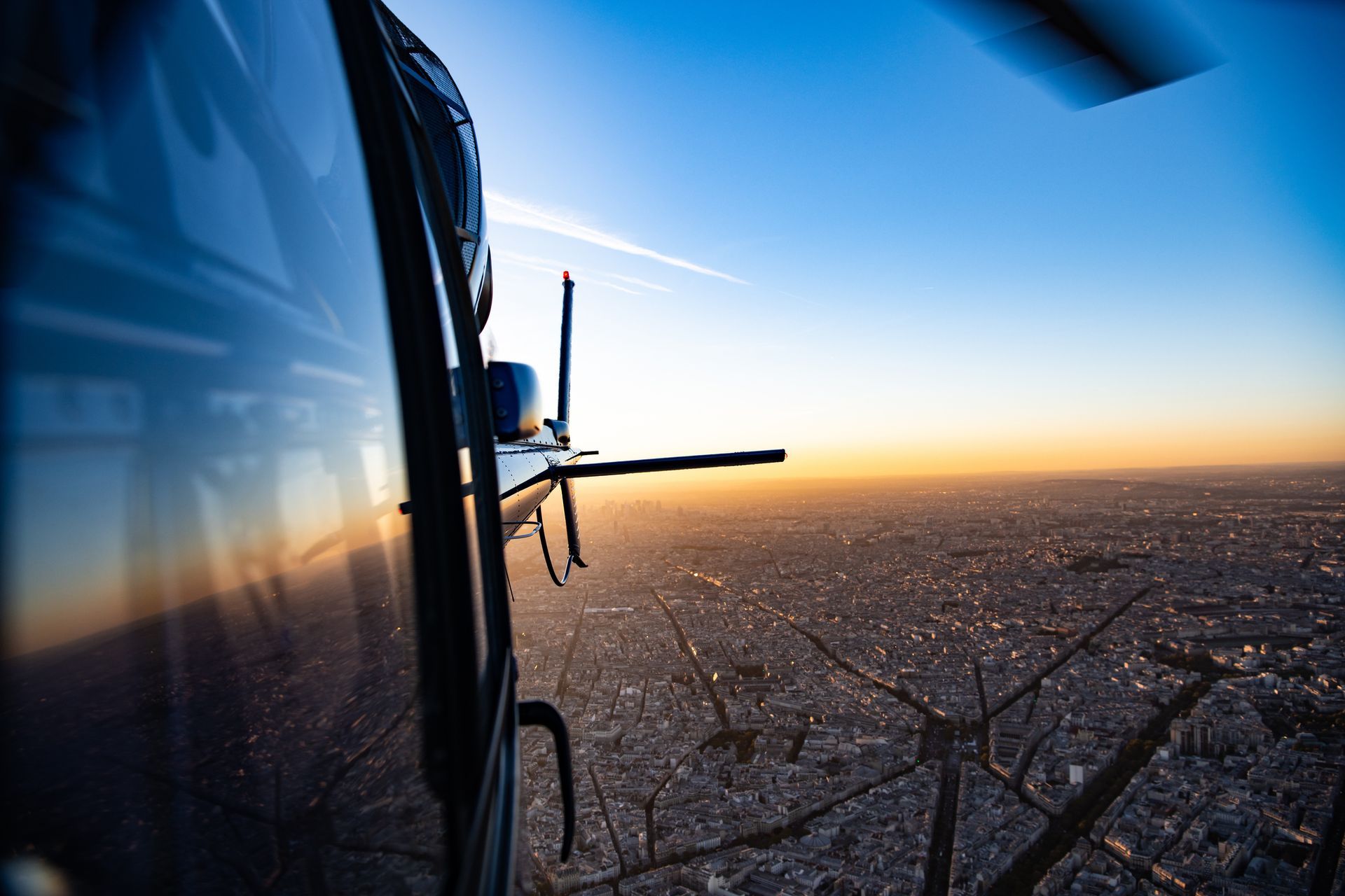 A helicopter is flying over a city at sunset.