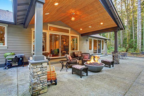 Large back yard with grass and covered patio with fire pit