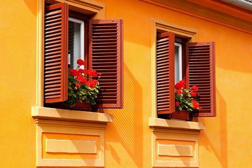 Red flowers on the windowsills of a yellow house